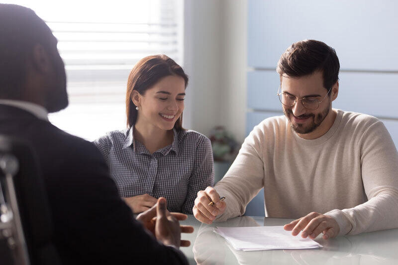 A couple is sitting at a table looking at papers and talking to a store representative.